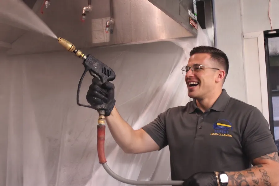 Expert Hood Cleaning technician pressure-washing a commercial kitchen exhaust hood